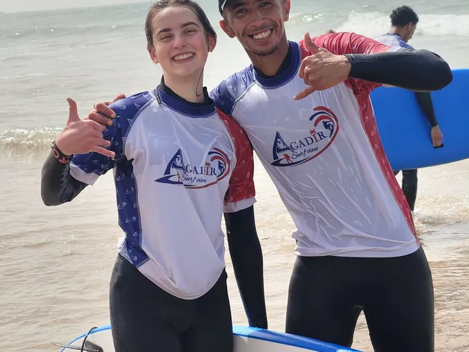 Solo surf student smiling next to coach Simo after a 1:1 surf session on Agadir Beach