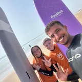 Three surf students with coach Simo after a group session